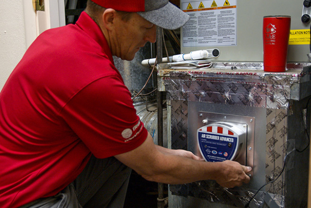 An A&E Plumbing, Heating and Air HVAC technician works to change the air filter on a heat pump.