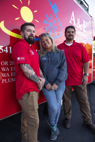 3 A&E employees standing in front of a bright red A&E company van.