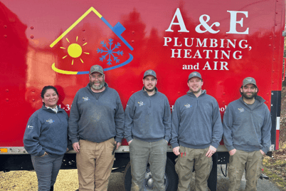 A picture of the A&amp;E Plumbing, Heating and Air plumbing team, standing in front of a red company van.