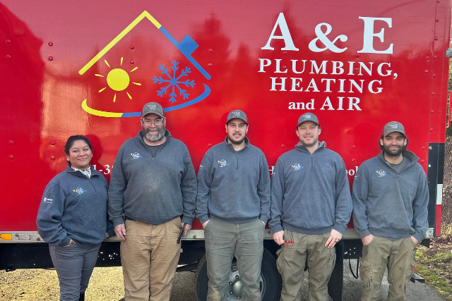 A picture of the A&E Plumbing, Heating and Air plumbing team, standing in front of a red company van.