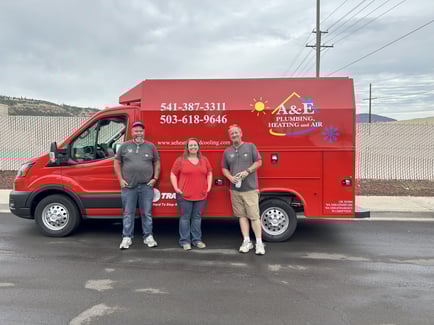 3 A&amp;E Plumbing, Heating and Air employees stand in front of an A&amp;E red van.