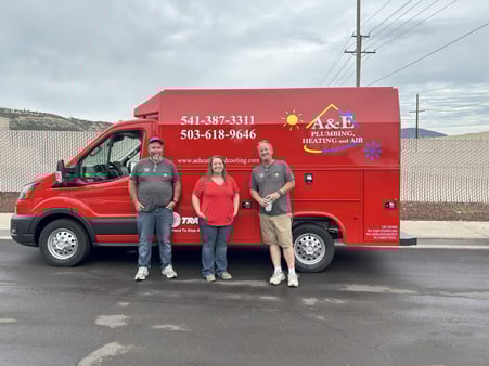 3 A&amp;E Plumbing, Heating and Air employees stand in front of an A&amp;E red van.