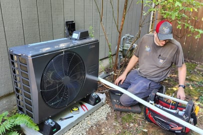 An A&amp;E Plumbing, Heating and Air HVAC technician works on an outdoor heating and cooling unit.