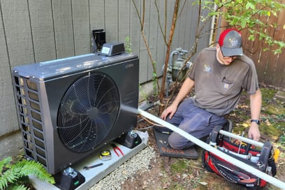 An A&amp;E Plumbing, Heating and Air HVAC technician works on an outdoor heating and cooling unit.