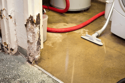 Water sits on the basement ground of a residential home after a plumbing backup emergency.