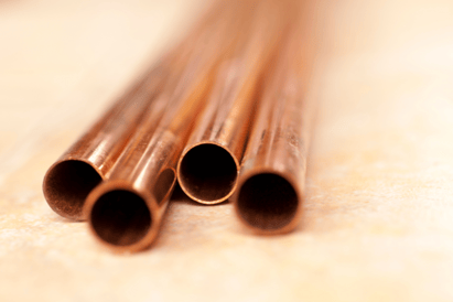 4 copper metal pipes sit on a light yellow background.
