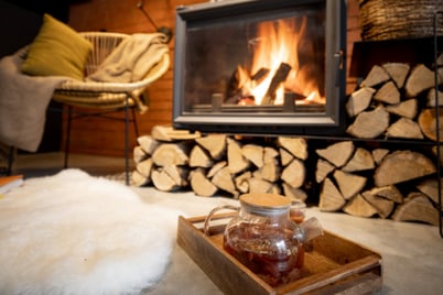 A fireplace is ignited beyond a pot of freshly brewed tea, showing how warm and comfortable the environment is.