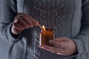 A woman lights a candle she intends to use to identify drafts in her home.