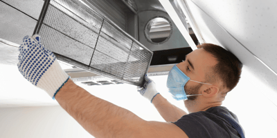 An HVAC tech changes the filter in a residential duct work system.