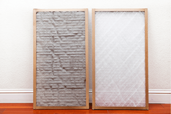 A dirty air filter sitting on a wall next to a clean air filter, showing the importance of replacing air filters consistently.