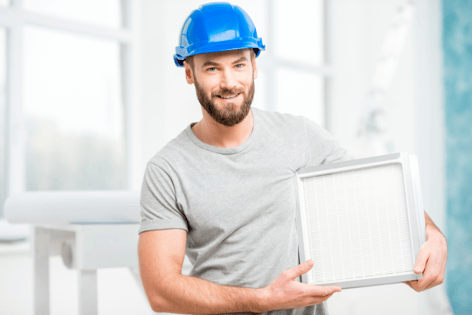 HVAC technician carrying a clean air filter with a blue safety helmet on.