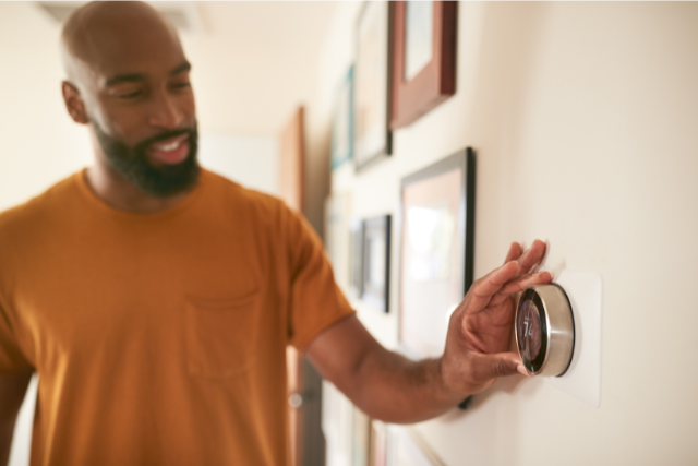 Man adjusting thermostat to ensure his home stays comfortable.