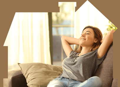 Woman sitting on couch, relaxing, with the frame of the photo in the shape of a house to represent a comfortable home.
