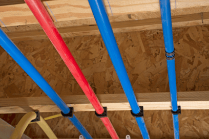 PEX plumbing pipes line a wall in a new construction home.