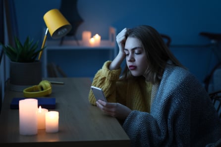 A woman sits at a desk with only candles after her power has gone out.