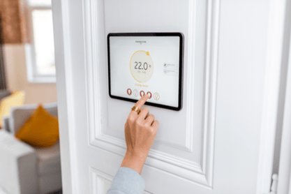 A hand reaches to adjust the temperature in their zone-controlled living room.