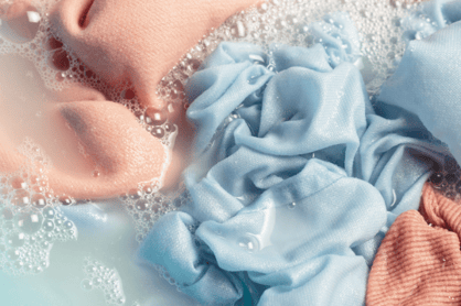 Soap suds surround linens in murky water.
