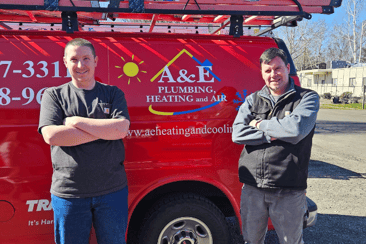 Two A&amp;E Plumbing, Heating and Air Techs stand in front of a red company van.