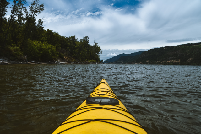 A person sits on a yellow kayak, expansive views of White Salmon, WA ahead of them.